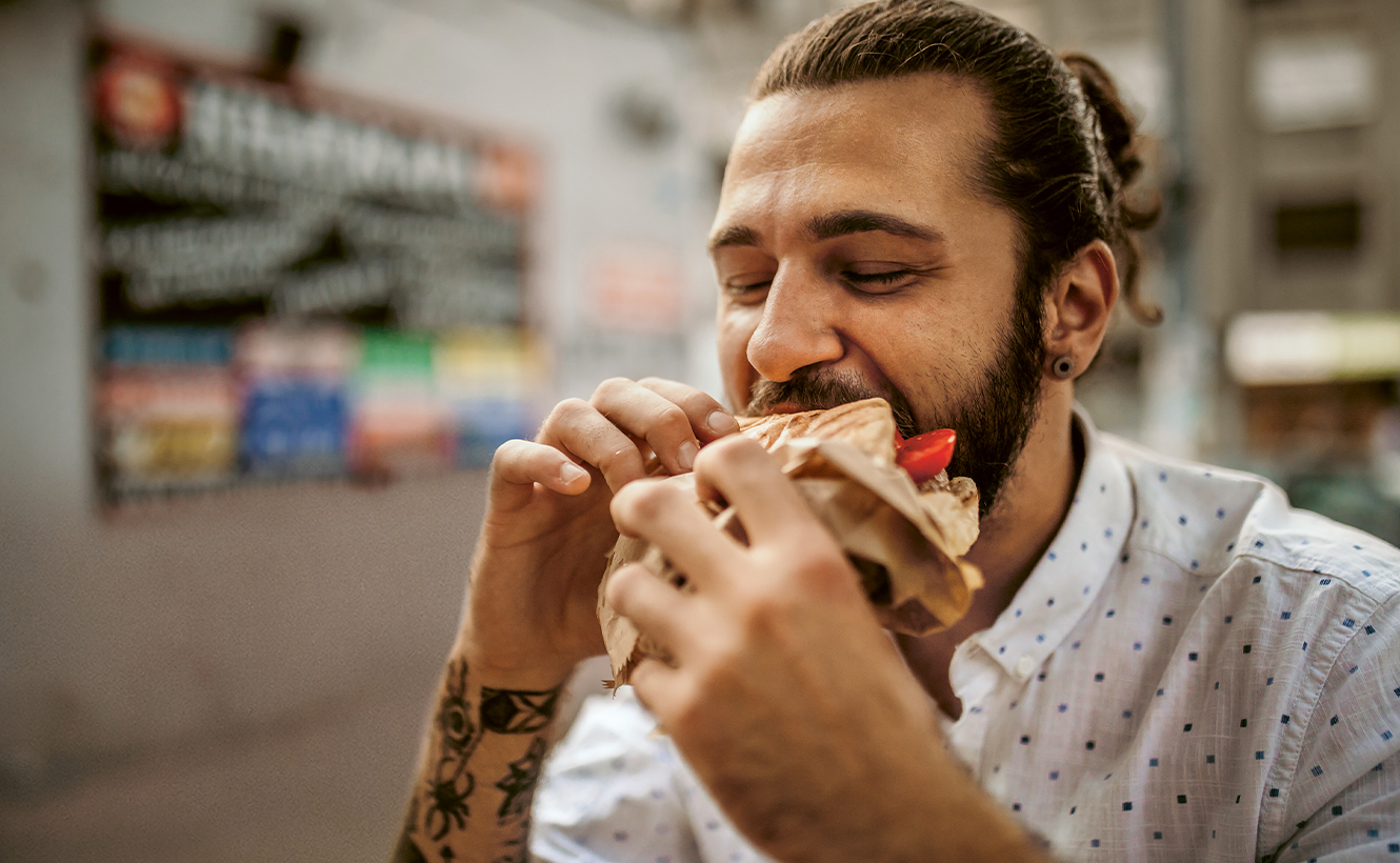 Mann beißt herzhaft in einen Döner