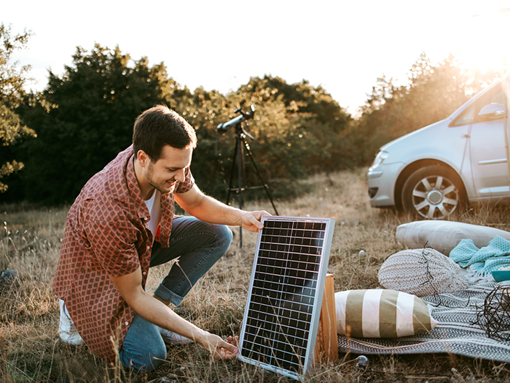 Mann stellt Solarmodul beim Camping auf